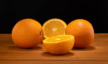 Fresh and juicy half and slice of orange fruit on a wooden table and black background.の写真素材