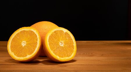 Halves oranges on a black background. Space for text. Sliced citrus fruits on a wooden table. Orange fruit on a black background.の写真素材