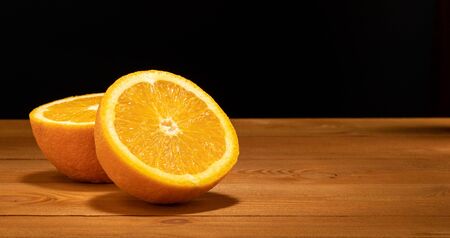 Halves oranges on a black background. Space for text. Sliced citrus fruits on a wooden table.の写真素材