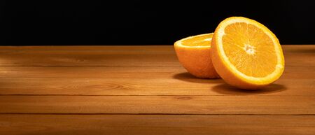Halves oranges on a black background. Space for text. Sliced citrus fruits on a wooden table.の写真素材