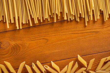 Uncooked dried pasta on wooden background. Space for text. Top view.の写真素材