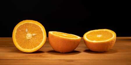 Fresh and juicy half and slice of orange fruit on a wooden table and black background.の写真素材