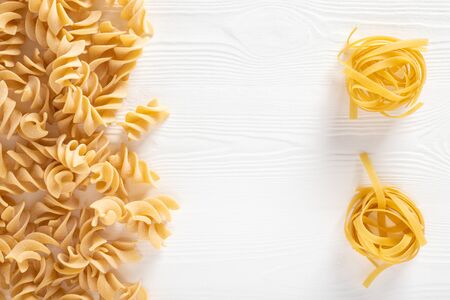 Uncooked dried pasta on wooden white background. Space for text. Top View.の写真素材