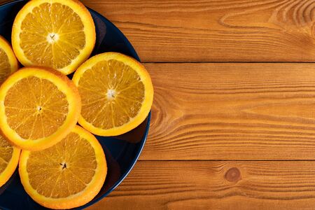 Sliced oranges on plate on wooden table. Copy space, top viewの写真素材