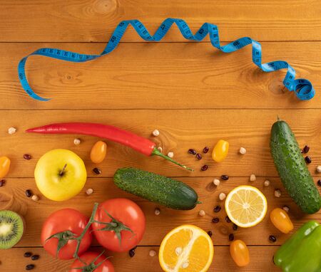 Fitness concept. Vegetables and fruit on a wooden table, measure tape, top view, healthy food conceptの写真素材