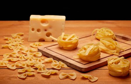 Raw pasta and cheese on a wooden table, healthy food conceptの写真素材
