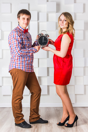The guy in trousers and shirt and a girl in a red dress with clockの写真素材