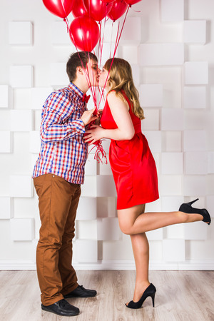 The guy in trousers and shirt and a girl in a red dress with red ballsの写真素材