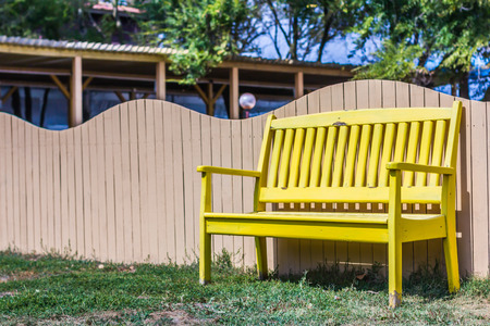 Wooden bench near wood fence under blue skyの写真素材