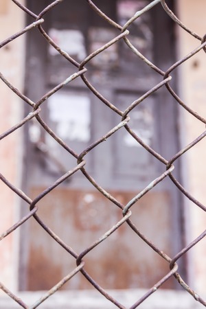 Rusty steel chain link or wire mesh as boundary wall. There is door behind the mesh.の写真素材