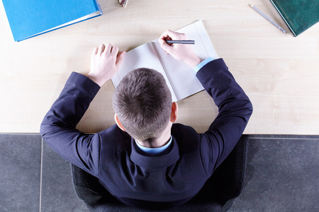 Boy sitting in a chair at the office table. Top viewの写真素材