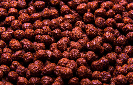 Chocolate breakfast cereal texture. Cereal balls as background. Chocolate corn balls wallpaper...
