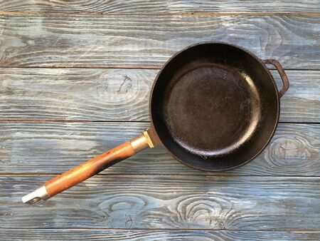 cast iron pan with wooden handle on a wooden blue tableの写真素材