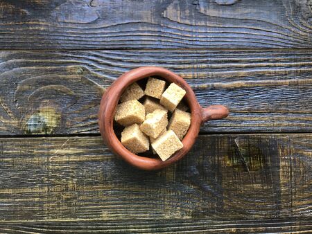 pieces of brown sugar in a ceramic mug on a wooden backgroundの写真素材