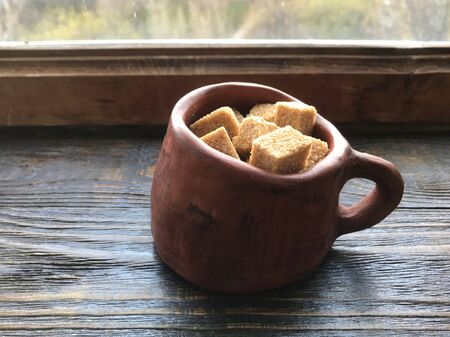 pieces of brown sugar in a ceramic mug on a wooden backgroundの写真素材