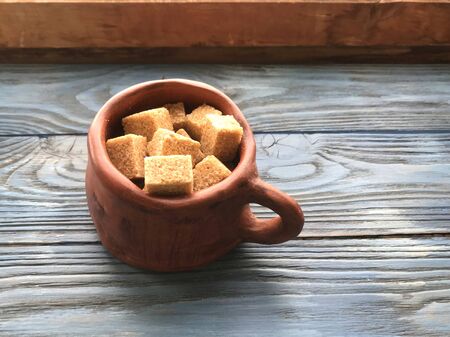 pieces of brown sugar in a ceramic mug on a wooden backgroundの写真素材
