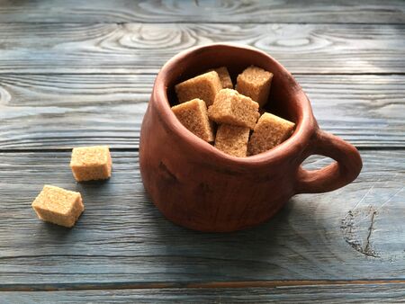 pieces of brown sugar in a ceramic mug on a wooden backgroundの写真素材