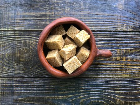 pieces of brown sugar in a ceramic mug on a wooden backgroundの写真素材