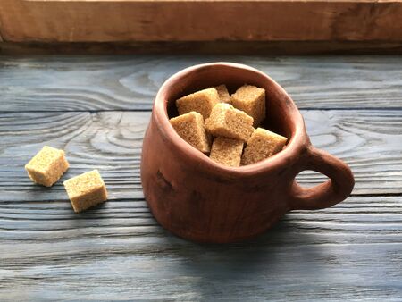 pieces of brown sugar in a ceramic mug on a wooden backgroundの写真素材