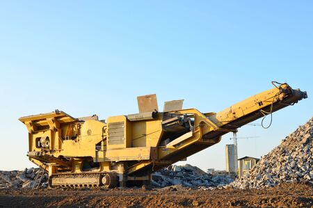 Mobile Stone crusher machine by the construction site or mining quarry for crushing old concrete slabs into gravel and subsequent cement productionの写真素材