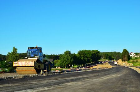 Asphalting construction works with commercial repair equipment. Road rollers leveling fresh asphalt...