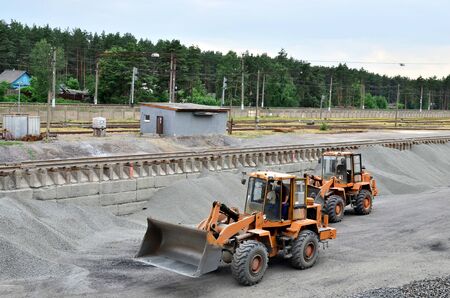 The wheel loader unloads crushed stone in a gravel pit. Unload bulk cargo with of the cargo railway...