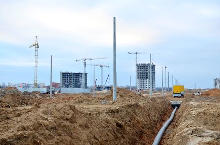 Laying of underground storm sewer pipes. Installation of water main, sanitary sewer. Plastic drainage pipe in ditch. Installation of concrete sewer wells in the ground at the construction site.の写真素材