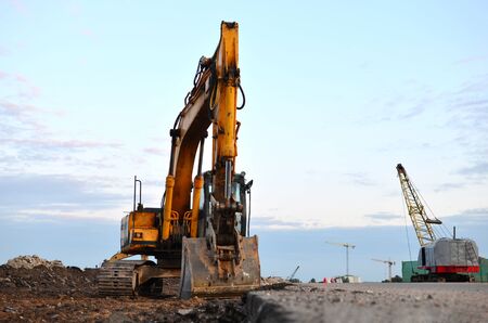 Large tracked excavator on a construction site. Road repair, asphalt replacement.  Loading of stone and rubble for its processing at a concrete factory into cement for construction work.の写真素材