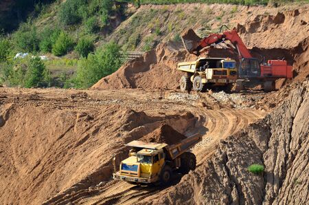 Excavator developing the sand on the opencast and loading it to the heavy dump truck. Processing of...