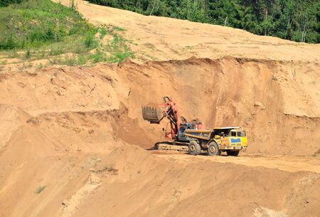 Excavator developing the sand on the opencast and loading it to the heavy dump truck. Processing of...