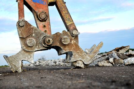 Excavator with hydraulic shears breaks asphalt on a construction site. Hydraulic shear crusher...