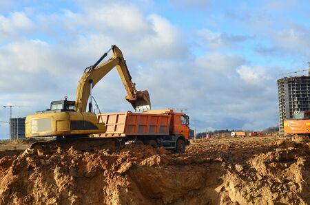 Excavator load the sand to the heavy dump truck on construction site. Excavators and dozers digs the...