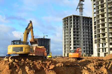 Excavator load the sand to the heavy dump truck on construction site. Excavators and dozers digs the ground for the foundation and construction of a new building. Apartment renovation programの写真素材