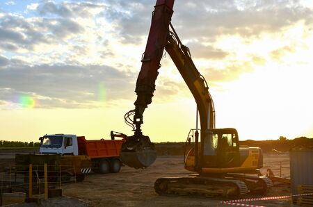 Excavator with grab bucket and telescopic boom for deep digging in the construction of underground...