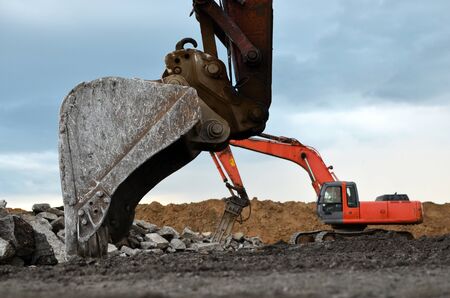 Excavator working in a construction site. Large metal iron ladle. Crusher bucket for crushing...
