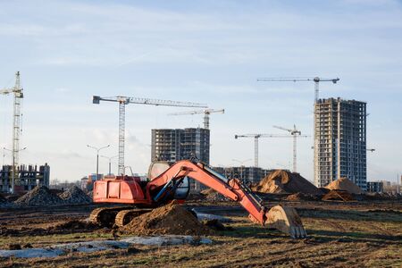 Excavator with a large iron bucket on a construction site during road works. Backhoe dig the ground...