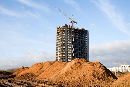 Tower cranes working at construction site against blue sky. Crane lifting a concrete bucket....
