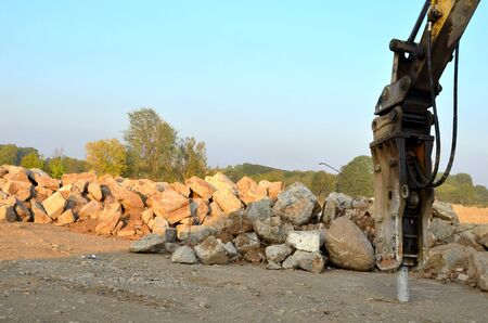Excavator with hydraulic breaker hammer for the destruction of concrete and hard rock at the construction site or quarry.  Jackhammer using without blasting method. Hard rock demolitionのeditorial素材