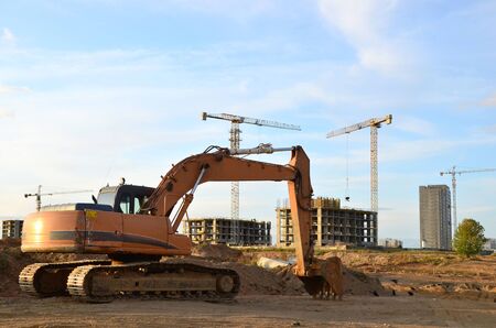Excavator digs the ground for the foundation and construction of a new building. Road repair, asphalt replacement, renovating a section of a highway, laying or replacement of underground sewer pipesのeditorial素材