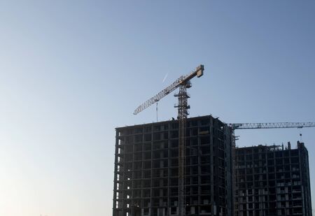 Hydraulic luffing jib tower cranes and workers being poured concrete into foundation. Cement pouring into formwork of building at construction site. Tower cranes constructing a new residential buildの写真素材