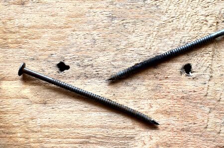 Old long construction nails on wooden background