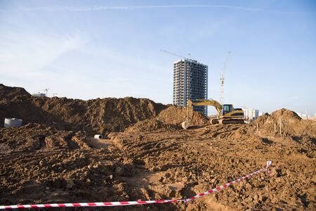 Excavator at building under construction. Backhoe digs the ground for the foundation and for laying...