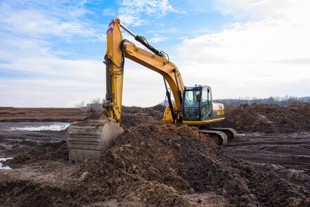 Excavator during earthmoving work at open-pit mining on blue sky background. Loader machine with...