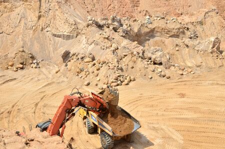 Excavator developing the sand on the opencast and loading it to the heavy dump truck. Processing of...