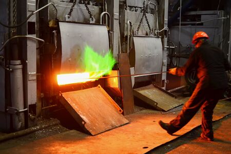 Steel quenching at high temperature in industrial furnace at the workshop of a forge plant. Process of cooling, heat treatmen. Blacksmith and metallurgical industry, steelmaking, hot rolling millの写真素材