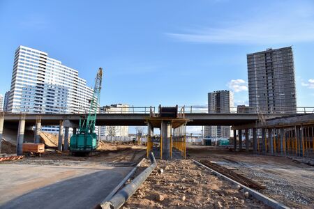 Roundabout and traffic bridge construction. Construction highway ramps and bridgeworks. Crane for formwork on bridge project works. Road work on traffic highway, road intersection junction and freewayの写真素材
