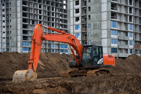 Excavator working at construction site on earthworks. Backhoe digs ground for the foundation and for...
