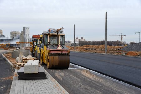 Paving roller machine during road work. Road roller at construction site for paving works. Screeding...