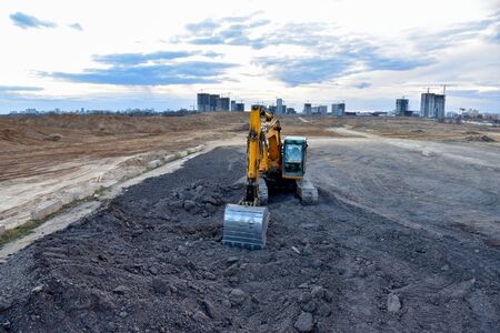 Excavator work at constrruction site on sunset background. Backhoe digs gravel and old concrete....