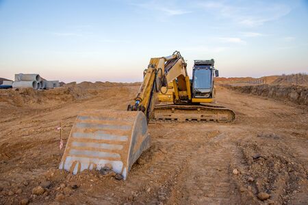 Excavator working at construction site on road work. Backhoe digs ground for the foundation and for...